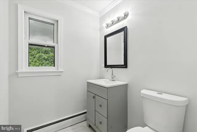 a bathroom with a toilet sink vanity and mirror