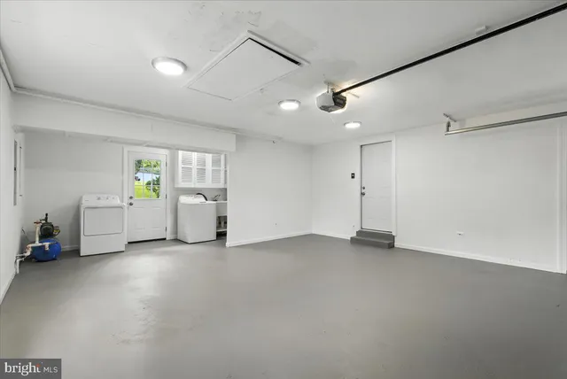 a view of an empty room with a window and kitchen view