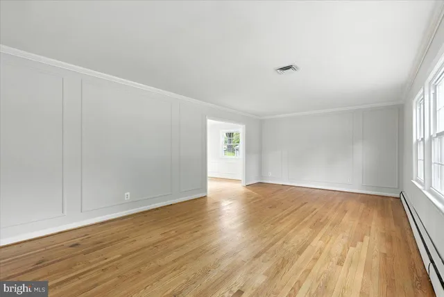 a view of an empty room with wooden floor and window