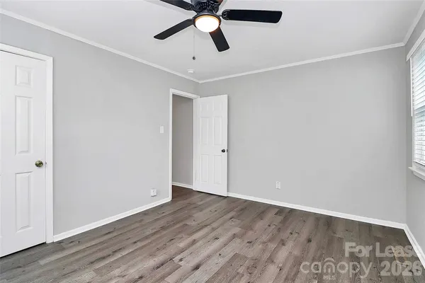 an empty room with wooden floor and ceiling fan