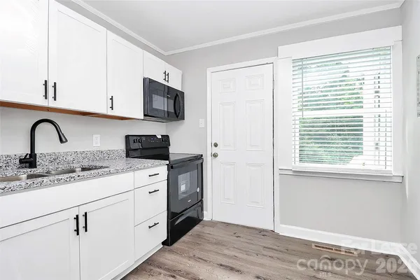 a kitchen with stainless steel appliances granite countertop a sink and a stove next to a window