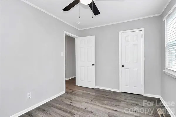 a view of an empty room with window and wooden floor