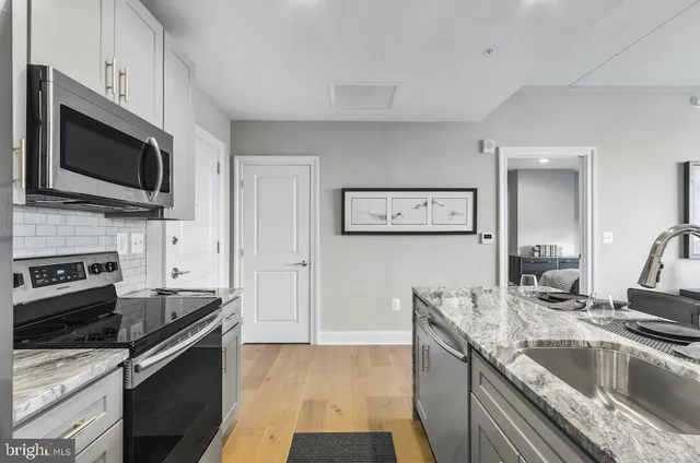 a kitchen with granite countertop a sink and steel appliances