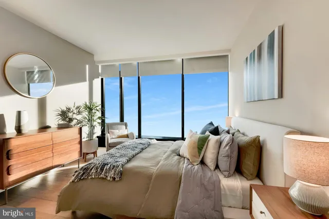 a bedroom with a bed a mirror and a large window