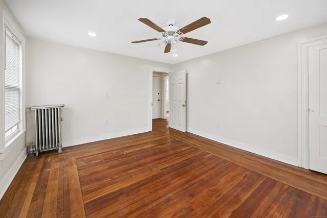 an empty room with wooden floor and ceiling fan