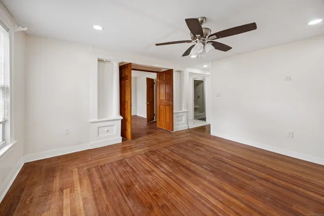 a view of an empty room with wooden floor and a window