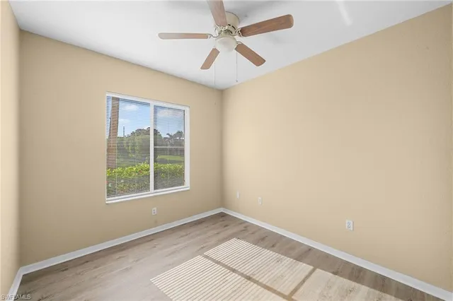 an empty room with windows and fan