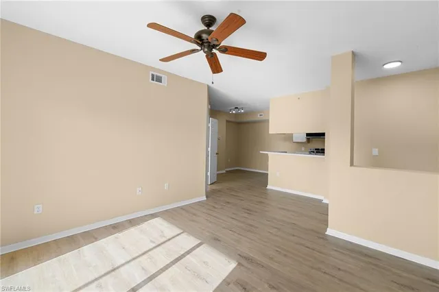 a view of empty room with wooden floor and ceiling fan