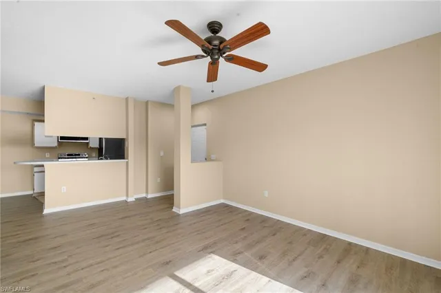 a view of empty room with wooden floor and ceiling fan