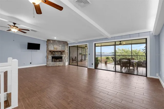 a view of an empty room with wooden floor and a fireplace