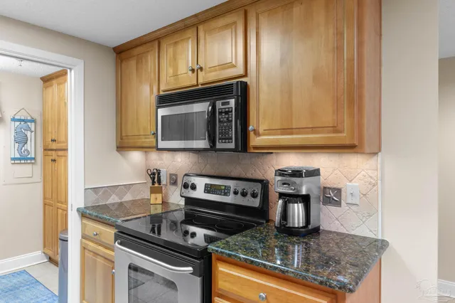 a kitchen with granite countertop a stove top oven microwave and cabinets