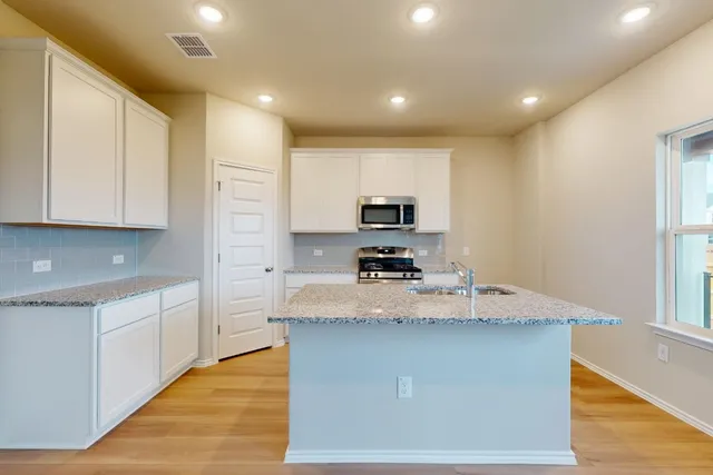 a kitchen with stainless steel appliances granite countertop a sink a stove and a refrigerator