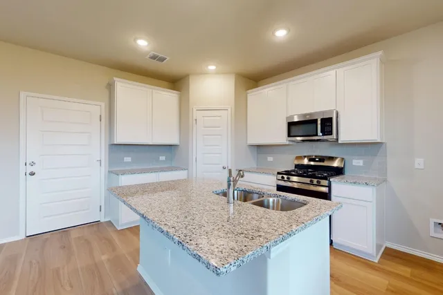 a kitchen with granite countertop a sink and a stove top oven with wooden floor