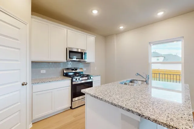 a kitchen with granite countertop white cabinets and a stove