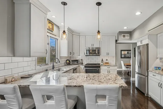 a kitchen with stainless steel appliances kitchen island granite countertop a sink refrigerator and cabinets