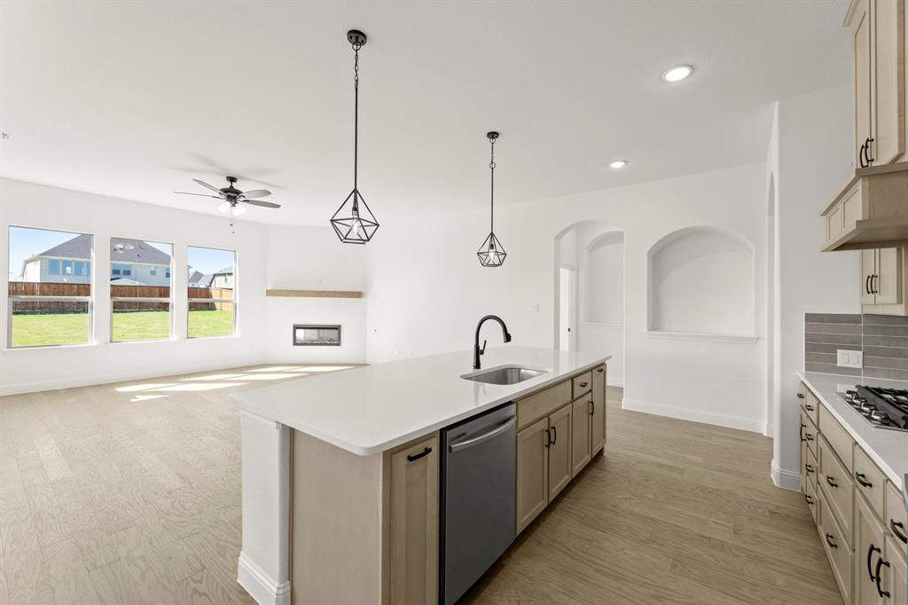 610 Tenor Drive Forney, TX 75126 - Photo 5 of 30 a open kitchen with stainless steel appliances granite countertop a sink a oven and a fireplace with wooden floor