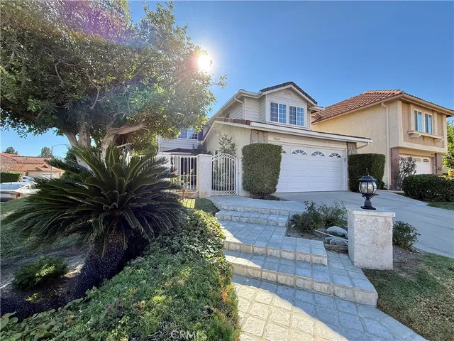 a view of a house with a yard plants and large tree