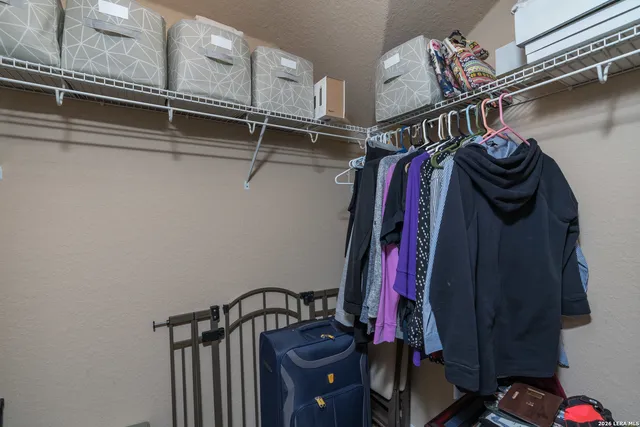 a view of walk in closet with clothes and shoes