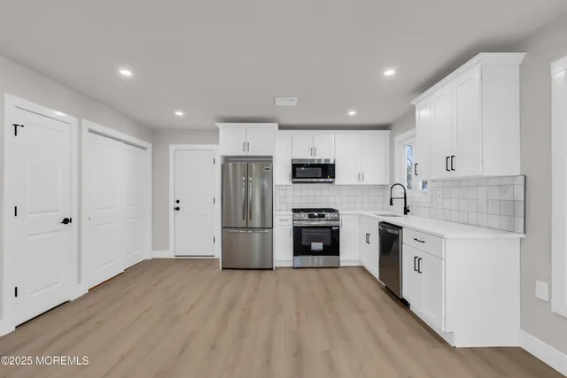 a view of kitchen with stainless steel appliances granite countertop a refrigerator and a stove top oven