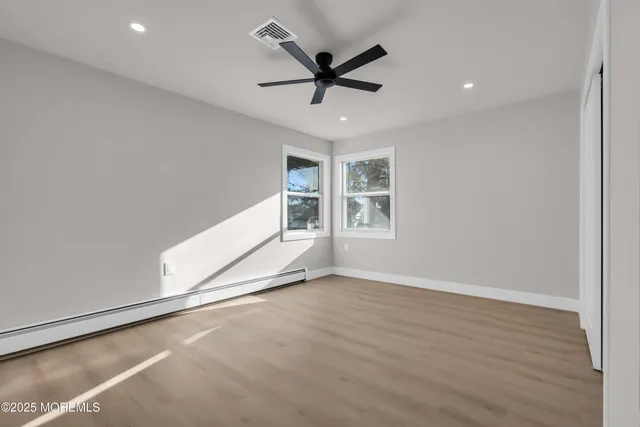 a view of empty room with wooden floor and ceiling fan