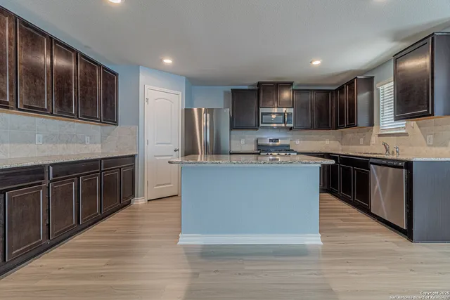 a kitchen with stainless steel appliances granite countertop a stove a sink dishwasher a microwave oven and a refrigerator