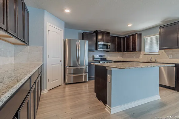 a kitchen with stainless steel appliances granite countertop a refrigerator a stove a sink and a microwave