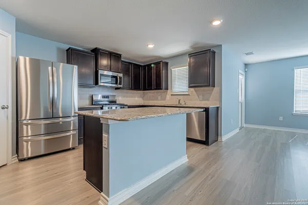 a kitchen with stainless steel appliances granite countertop a refrigerator and a stove top oven