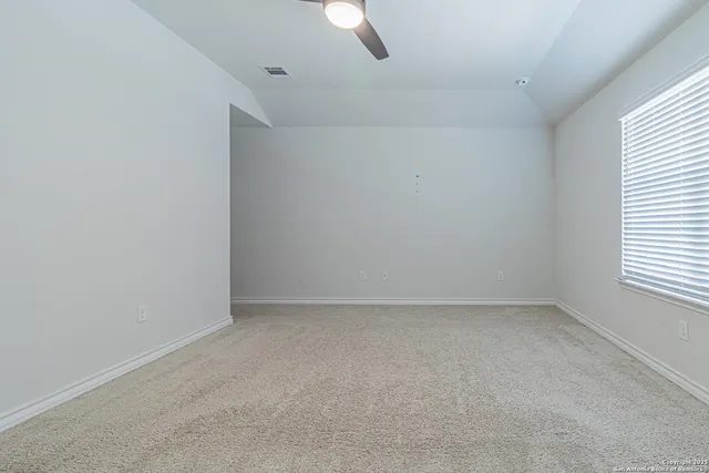 an empty room with a window and ceiling fan