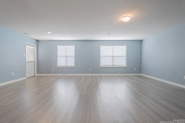 an empty room with wooden floor and window