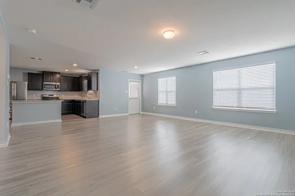 an empty room with wooden floor and windows