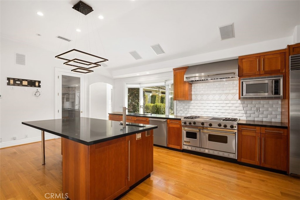 a kitchen with stainless steel appliances granite countertop hardwood floor sink stove and wooden cabinets