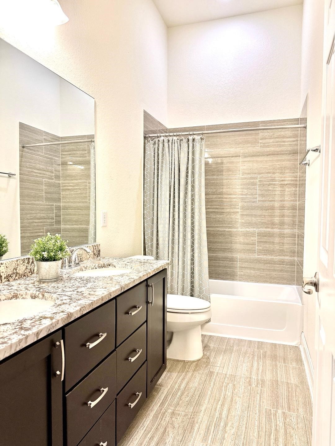 1110 Penny Ranch Lane Katy, TX 77494 - Photo 24 of 31 a bathroom with a granite countertop sink toilet a mirror and bathtub