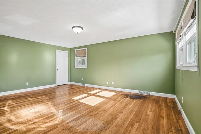 a view of a big room with wooden floor and windows