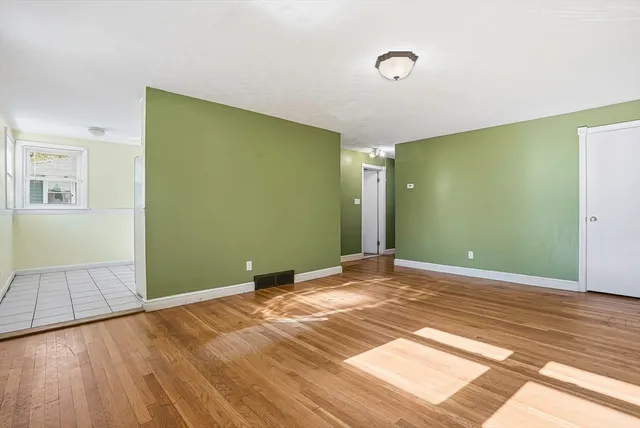 a view of an empty room with wooden floor and closet