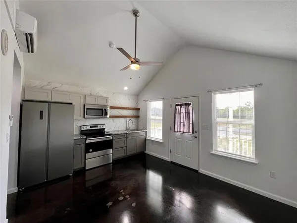 a kitchen with stainless steel appliances kitchen island granite countertop a refrigerator a sink dishwasher a stove and a refrigerator with wooden floor