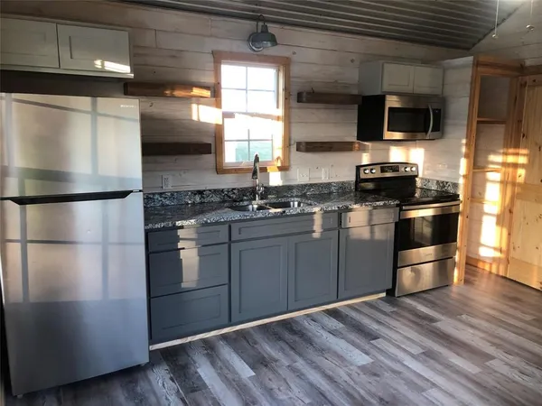 a kitchen with stainless steel appliances kitchen island granite countertop a stove a refrigerator and a microwave