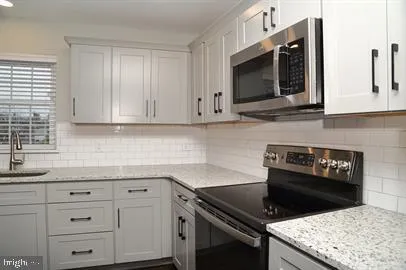 a kitchen with granite countertop white cabinets and stainless steel appliances
