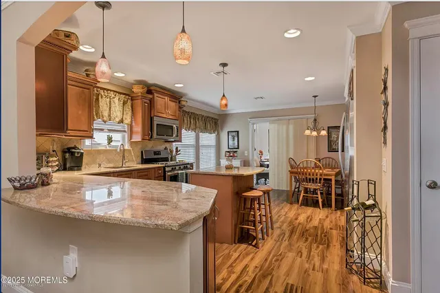 a kitchen with stainless steel appliances granite countertop a stove top oven a sink dishwasher a dining table and chairs with wooden floor