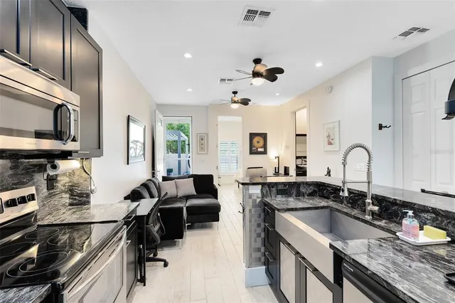 a kitchen with granite countertop stainless steel appliances a sink stove and cabinets