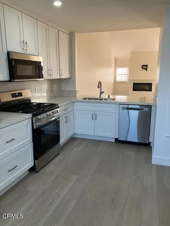 a kitchen with granite countertop white cabinets and stainless steel appliances