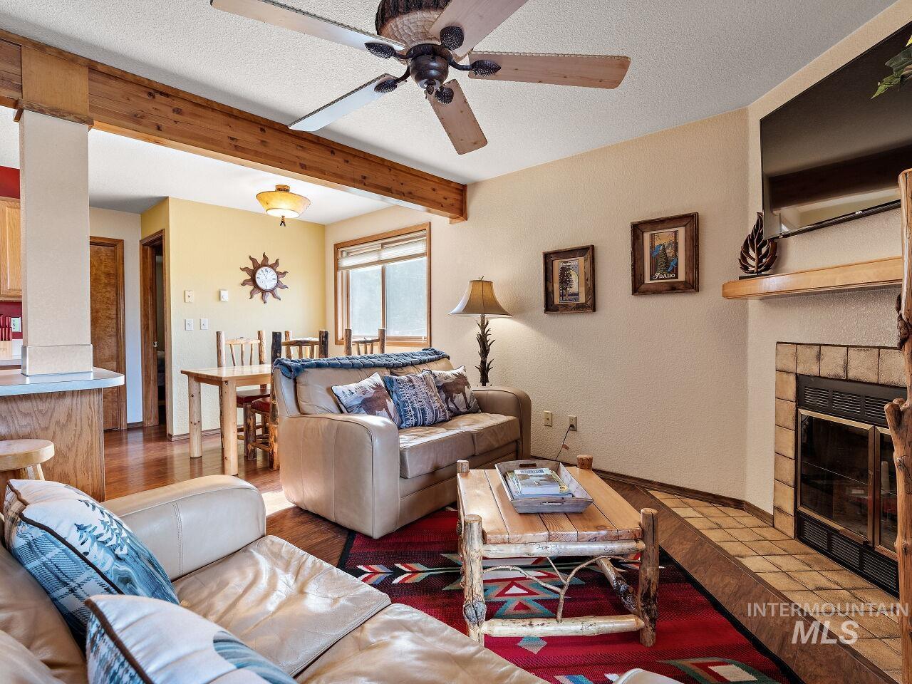 601 Hemlock Street, Unit 10 McCall, ID 83638 - Photo 11 of 43 Living room featuring a ceiling fan, beam ceiling, a tile fireplace, a textured ceiling, and wood finished floors