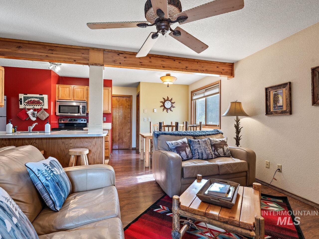 601 Hemlock Street, Unit 10 McCall, ID 83638 - Photo 12 of 43 Living area with a ceiling fan, beam ceiling, wood finished floors, a textured ceiling, and a textured wall