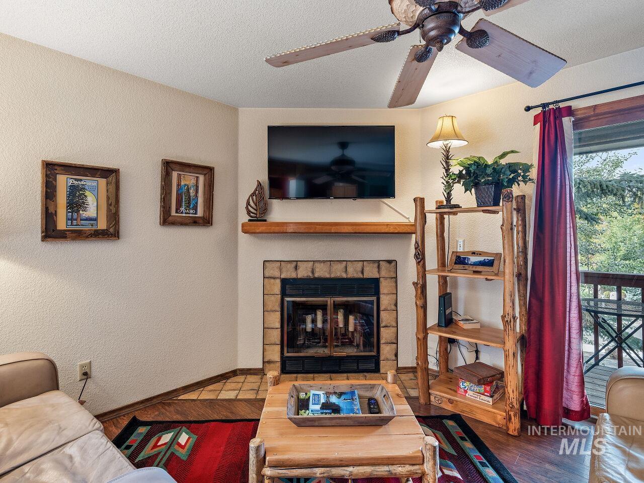 601 Hemlock Street, Unit 10 McCall, ID 83638 - Photo 14 of 43 Living room with a ceiling fan, wood finished floors, a brick fireplace, and a textured ceiling