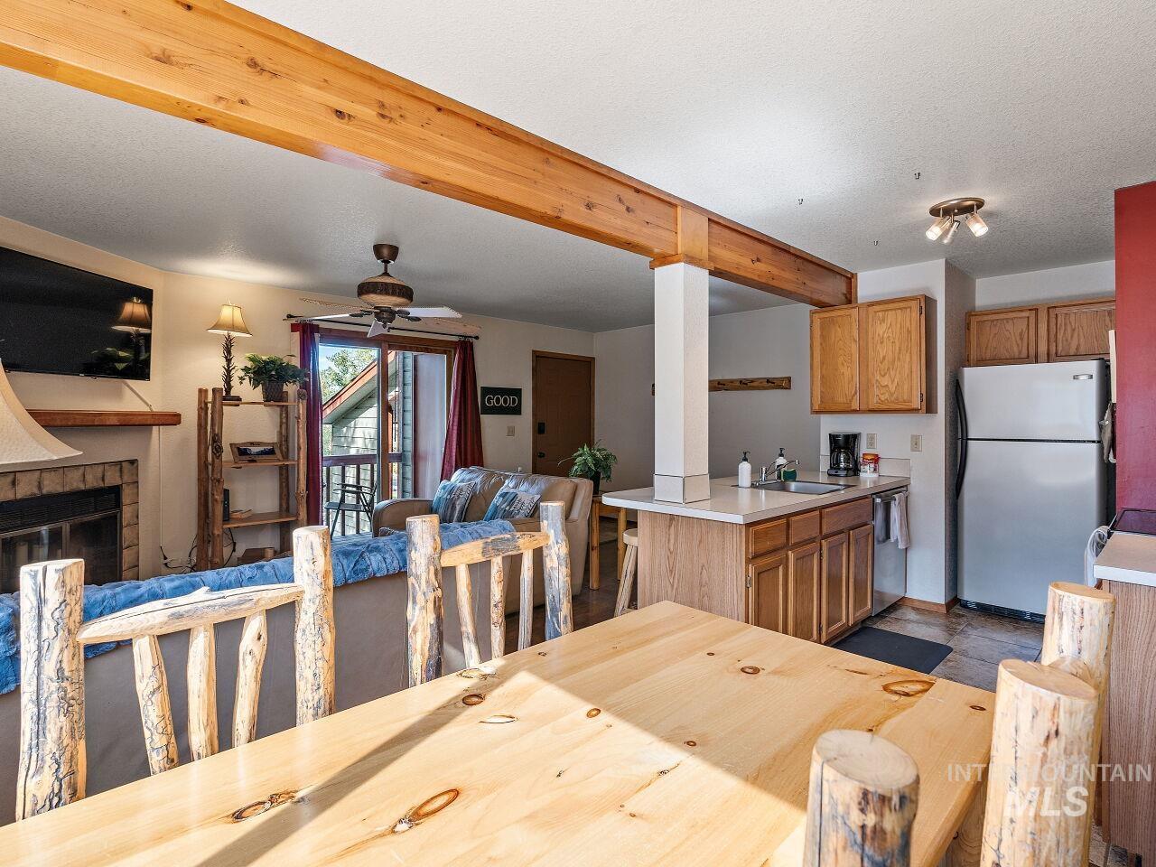 601 Hemlock Street, Unit 10 McCall, ID 83638 - Photo 18 of 43 Dining area with a ceiling fan, a glass covered fireplace, and beam ceiling