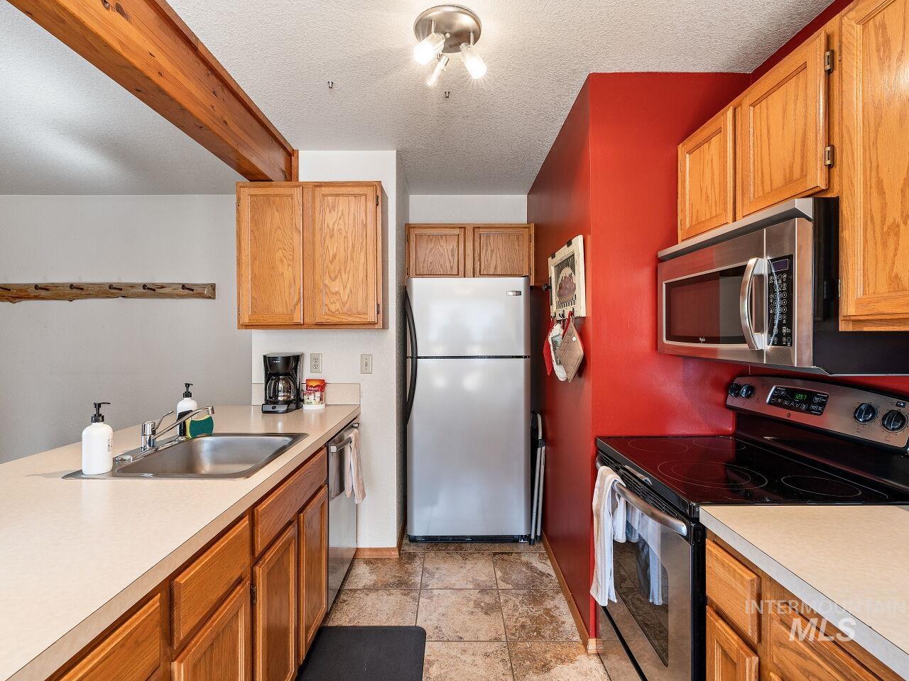 601 Hemlock Street, Unit 10 McCall, ID 83638 - Photo 20 of 43 Kitchen with stainless steel appliances, light countertops, brown cabinetry, and a textured ceiling