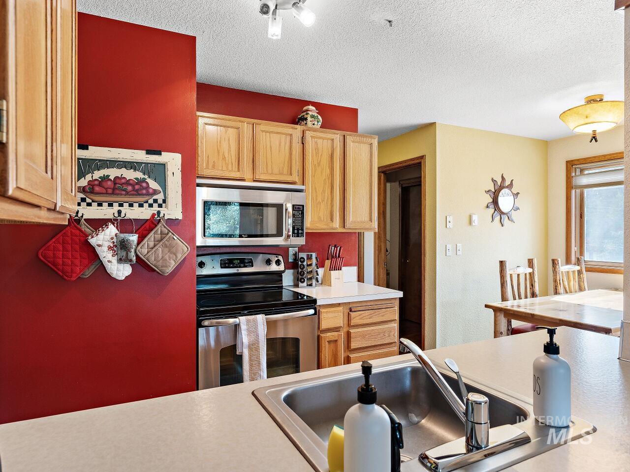 601 Hemlock Street, Unit 10 McCall, ID 83638 - Photo 23 of 43 Kitchen with appliances with stainless steel finishes, light countertops, a textured ceiling, and light brown cabinetry