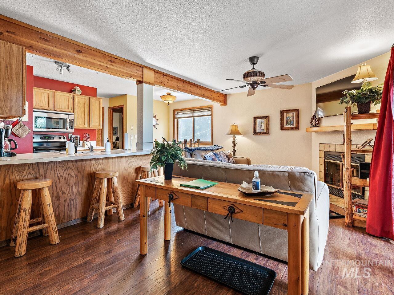 601 Hemlock Street, Unit 10 McCall, ID 83638 - Photo 25 of 43 Living room with wood finished floors, ceiling fan, beam ceiling, a textured ceiling, and a tiled fireplace