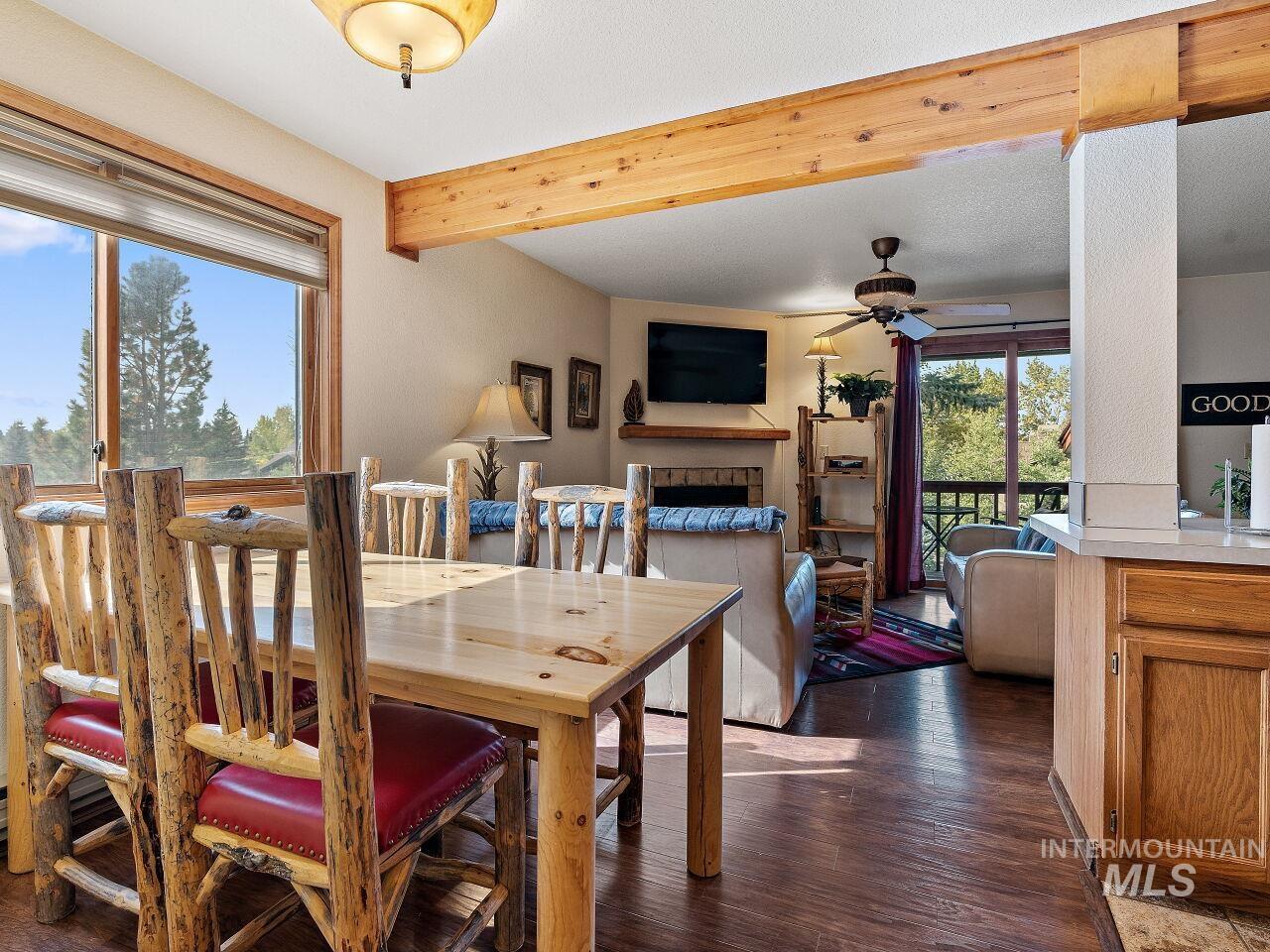 601 Hemlock Street, Unit 10 McCall, ID 83638 - Photo 27 of 43 Dining room featuring ceiling fan, dark wood-style flooring, a fireplace, and beamed ceiling