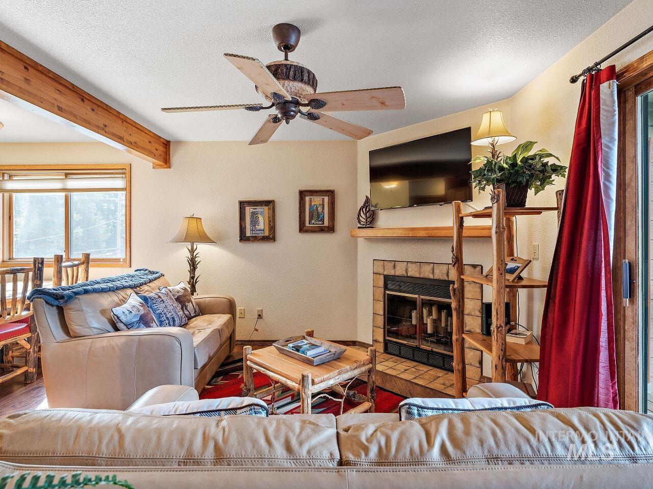 601 Hemlock Street, Unit 10 McCall, ID 83638 - Photo 9 of 43 Living room with ceiling fan, a tile fireplace, a textured ceiling, wood finished floors, and beam ceiling
