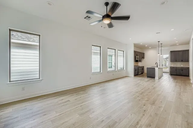 a view of an empty room with a window and wooden floor